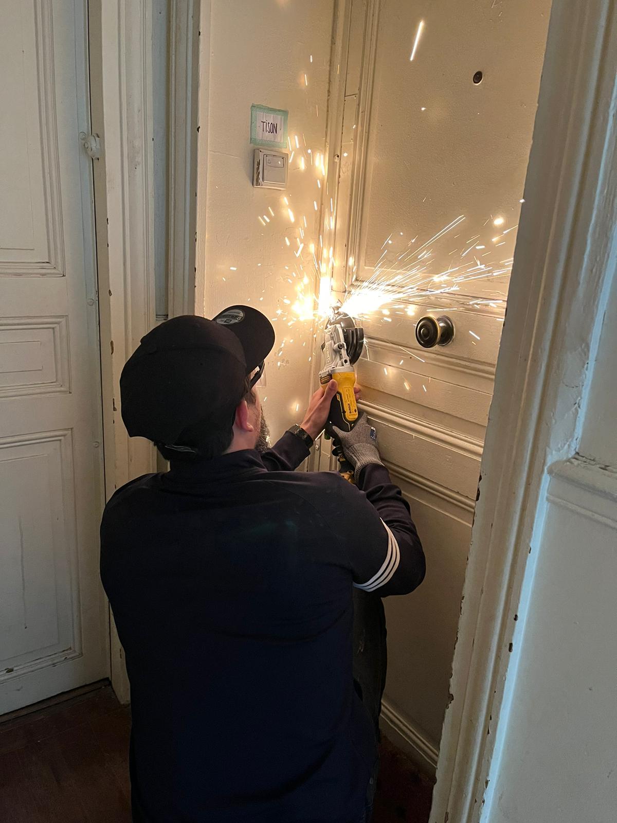 Dépannage d'urgence un artisan en train d'ouvrir une porte avec du matériel professionnel.